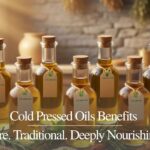 Premium cold pressed oils in glass bottles on a rustic wooden table with a Himalayan farm background.